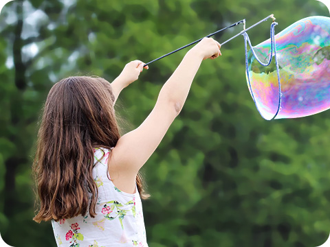 A girl playing with Soap Bubble with a blurred background